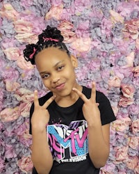 a young girl posing in front of a pink flower wall