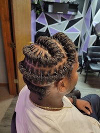 a man sitting in a chair with his hair braided